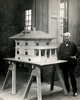 Inventor Thomas Edison stands next to a model of a "single-pour" concrete home, a progenitor of today’s prefab.
