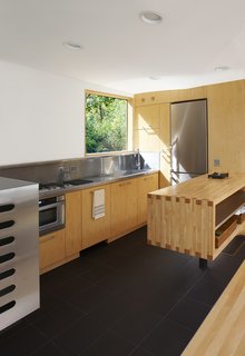 The stainless-steel-and-maple kitchen, which was completely pre-built as part of the module before being plopped onto the site, has a Flor-Gres recycled porcelain tile floor.