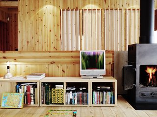Knotty by Nature - Photo 12 of 25 - Exposed pine boards dominate the interior, giving a subtle, warm backdrop to the splashes of color that his stove and collection of books provide.