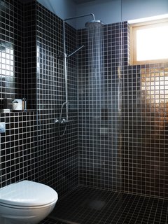 Knotty by Nature - Photo 18 of 25 - Simple black tiles and a basic, exposed showerhead kept costs down, allowing other parts of the house to function as the showpieces.