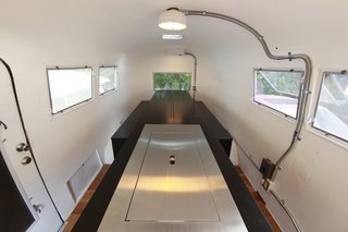 Hide and Sleep - Photo 1 of 10 - To maximize the small space inside the Airstream, Suzuki removed the existing structures and added a central island the follows his kenchikukagu style of design. Near the door (front of photo), a sink and cook top is hidden under the steel cover. At the rear (back of the photo), a dining table transforms into a set of twin beds. Photo by Sadamu Saito.