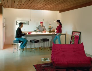 How Good Idea Studio Revamped a 1924 Clapboard House on a $62,000 Budget - Photo 7 of 11 - Thanks to a skylight and the absence of conventional wall cabinets, the kitchen looks more like an airy extension of the living room than a dedicated space for cooking. With the sink, oven, and storage tucked behind and a long countertop in front, the island serves as a more versatile built-in feature.