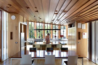 Melissa Schollum stands at the brass island bench in the kitchen. O’Sullivan, who designed and built the house, spent many hours creating the wooden joinery (including the tall, slender windows and their timber shutters) and the intricate ceiling. The cupboards under the marble bench in the kitchen are made of glass to allow more light into the space. The dining table and chairs were designed by Sam Haughton of IMO.