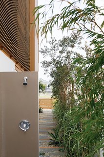 These 13 Outdoor Showers Will Make You Consider One For Your Own Yard - Photo 9 of 13 - After a day at the beach, an outdoor shower tucked toward the back of the house allows everyone to rinse off without tracking sand indoors.
