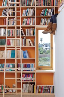 Coast Docs - Photo 2 of 13 - To make the most of 13-foot-high ceilings that help draw hot air out through second-floor windows and doors, designer Daniel Garness painted select walls with playful color and lined them with maple plywood bookcases. Library ladders (about $1,500 each from Alaco Ladder Company) provide access to reading material and a sleeping loft.