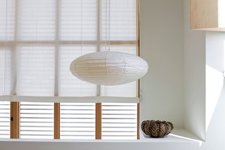 Coast Docs - Photo 11 of 13 - Inexpensive muslin makes a lightweight and luminous covering for windows and the pivoting glass door in the kitchen. While the roll-up shades fabricated by Van Nuys Awning Co. resemble a ship’s sails, the hardware for the cords calls to mind boat cleats. Both are fitting nautical references as the house is located only blocks away from the ocean.