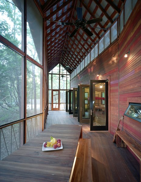 A view back toward the entrance. The purlin ceiling beneath the porch’s gabled Galvalum roof is made up of two-by-four cedar strips. A frieze of screened openings runs the length of the building, allowing a cross-breeze and extra light in, while ceiling fans keep the air circulating in summer. “Animals, from deer to raccoons to all kinds of birds, come right up to the porch,” says Panton. Photo 10 of Texas Bunkhouse modern home