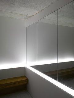 A mirror near the mailboxes in the lobby gives the illusion of more space. A team from Lighting Planners Associates, based in Japan, added the uplights behind the bench for effect. The architectural firm left the ceilings raw concrete to make the space "more enigmatic," says Schultz.