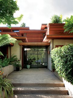 As the house is situated on a steep slope, visitors enter only to be whisked upstairs to the main living space. The facade was designed by Bob Hatfield in 1996. A new glass and steel door, designed by Chris Deam and fabricated by Sand Studios, was added in the renovation.