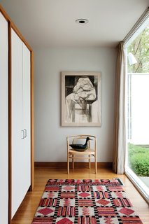 The main entry, located off the front courtyard is more practical than grand. The door opens onto a PK15 chair by Poul Kjaerholm and built-in coat cabinets that direct movement to either side of the hall and into the living area.