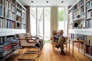 The library is lit by the front courtyard. The chartreuse vent, originally painted vermilion, is the one architectural color inside the house. Two Cantilever Cane chairs by Mies van der Rohe face Isaacson as he rests upon a Pernilla easy chair by Bruno Mathsson.