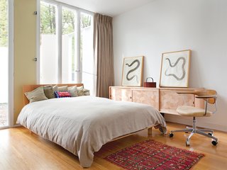 The second bedroom has an eclectic mix of textiles and textures: replicas of the original curtains, a custom wood credenza by Gerald Curry, a bright pillow made by a friend, bed linens from Finland, and a rug from Morocco.