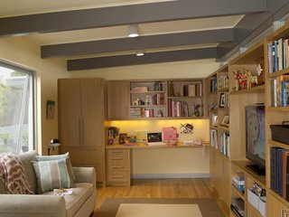 The new family room has a built-in desk for the daughter, who often uses the room to hang out with friends. The kitchen is just on the other side of the wall at right and shares its row of interior clerestory windows.