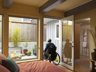 The new, more intimately scaled master bedroom leads to an adjacent patio, which was repaved to gently slope from the doorway to new drains, which solved both an access and a water issue. Braitmayer planted quick-growing bamboo in galvanized troughs for privacy. At right is the seamless passage to the master bathroom. "There are no longer raised thresholds in the house," notes Braitmayer.