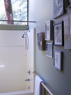 A salon-style hanging of art and the wooden handrail-cum-towel rack give the bathroom a handful of subtly stylish touches.