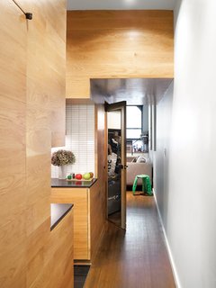 White oak paneling imbues uniformity and warmth into the hallway, kitchen, and living spaces.