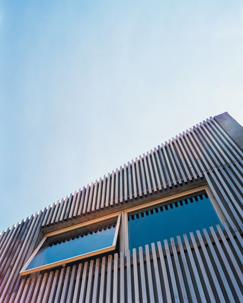 A cedar-slat rain screen hangs on the facade of Denis Carpenter’s concrete house in Jersey City, softening its appearance and adding a modest dash of color. Carpenter keeps the awning-style windows open in the spring and summer, creating a draft that compensates for the lack of an air-conditioning system.