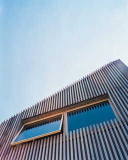 A cedar-slat rain screen hangs on the facade of Denis Carpenter’s concrete house in Jersey City, softening its appearance and adding a modest dash of color. Carpenter keeps the awning-style windows open in the spring and summer, creating a draft that compensates for the lack of an air-conditioning system.