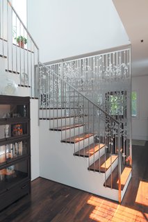 An 1850 schoolhouse in Milford, Pennsylvania - Photo 9 of 11 - Andrew Magnes’s hanging screen composed of aluminum circles and lines, cut with a CNC water jet, separates the entry from the staircase and rear kitchen area.