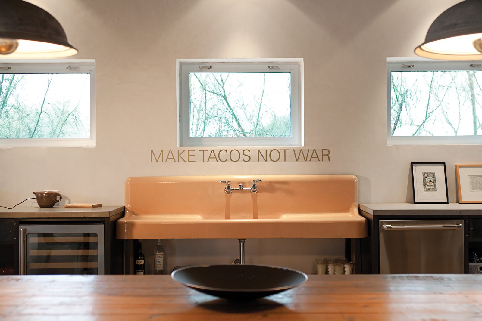 In the kitchen, Make Tacos Not War, by San Antonio-based artist Alejandro Diaz, is mounted over a putty-colored sink Hill Salvaged from a demolition yard.