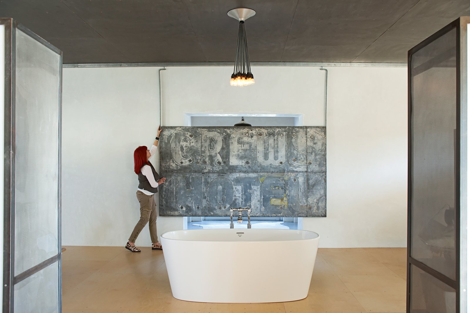 Seeking a large-scale artwork that could also act as a privacy screen for her bedroom, Hill hung the vintage hotel sign she scored at Installations Antiques in Houston on a sliding track. When she wants to block the view from the backyard, she simply slides the sign along its blackened-steel track into place in front of her doorway.