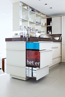 The cabinetry in the kitchen and elsewhere is crafted from discarded, chopped-up billboards. White paint camouflages their fronts, but when pulled open, their colorful sides offer a glimpse of their previous life as streetside advertising.