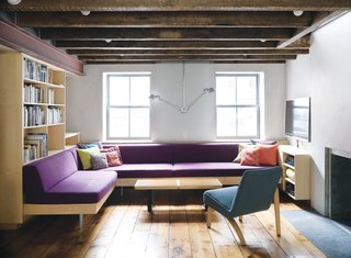 Family Home Renovation in Brooklyn - Photo 1 of 28 - Facing the front facade on the English basement level, a sectional of Dixon’s design punctuates the otherwise neutral hues with a stately purple. The lamp is a double-suspension Tolomeo from Artemide. The reupholstered Thonet chair lends balance to the room through its own asymmetry.