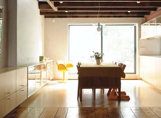 Family Home Renovation in Brooklyn - Photo 2 of 28 - Brightened by light from the backyard, the built-in credenzas and kitchen cabinetry are by JKK Woodcraft. A Kartell FL/Y pendant lamp bridges the glass and wood details.