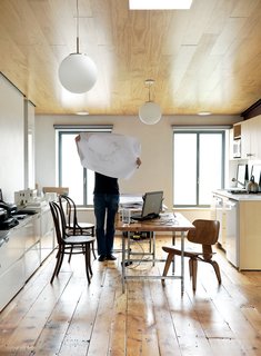 Family Home Renovation in Brooklyn - Photo 3 of 28 - Dixon inspects a drawing in the couple’s shared office on the home’s top floor. The space features a sloping ceiling that rises to ten feet at one end. The new wood of the inserted ceiling counterpoints the vintage pumpkin pine floorboards underfoot.