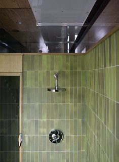 Family Home Renovation in Brooklyn - Photo 28 of 28 - Green Heath tile, with their signature unevenness, provide a warm touch to the modern space. A cut-out in the glass allows the bather to dial in the right temperature on the Kohler fixture before stepping into the shower.