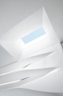 The clients embraced the material because it is kidproof—any marks can be cleaned easily and the matte finish resists fingerprints. The structure was built off-site, brought into the apartment in pieces, installed on a wooden skeleton, and then sanded over a three-day period to achieve a seamless integration with the back wall and the skylight overhead. "It’s kind of a melting design that comes from above and goes down the shelves," says Schoenenberger.