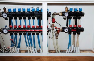 The radiant-heating system's pipes and gauges hide in a closet.