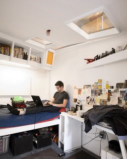 Communal Living on a Budget in Brooklyn - Photo 5 of 13 - Justin Smith’s cell-like quarters are packed full of books and art. "Each room gets the bare minimum: a sleeping area, a desk, and storage," explains Ionescu. The designers carefully laid out the space so that the beds in each room are as far apart from each other in plan as possible, in order to get as much privacy as possible.