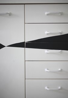 Since the couple knew they'd soon rip up the kitchen during a major pipe replacement and renovation, Susanna devised a cheap and easy way to prettify the nondescript cabinets in the meantime: she cut triangles out of black contact paper and affixed them to the cabinet fronts.