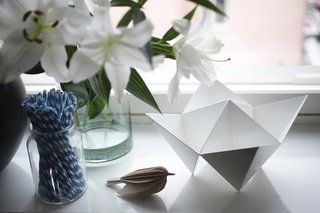 Susanna's skill as a stylist is evident in the apartment's many eye-catching arrangements of objects: here, a paper bird, a origami bowl, and a jar of striped paper straws.
