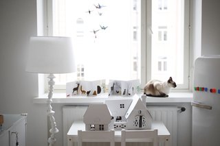 The flags and other bright accents bring a shot of color and fun to the serene, white-filled bedroom.