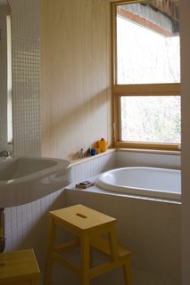 The bathroom features a Duravit sink that was incorrectly ordered for a job by the contractor and then donated to Hale. The stools are from Ikea, the tub was salvaged, and the tiles were surplus from another project.