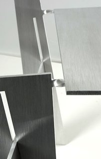 Each chair is folded from a sheet of 6-mm-thick aluminum. The points where the metal is twisted become delicate-looking hinges.