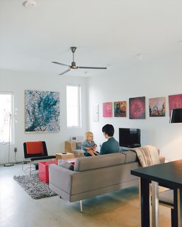 Green Urban Housing in Philadelphia - Photo 9 of 11 - Courtney and Teague play in the living room opposite a Perch lounge designed by Eric Pfeiffer for Offi. The paintings behind the TV are by artist Chris Clark.