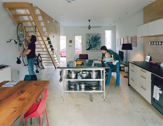 Green Urban Housing in Philadelphia - Photo 1 of 11 - The long, rectangular bottom floor is one uninterrupted space. Bikes live beneath the stairs, and the kitchen island is a center of activity. The dining table was made by Bench Dog Design and the Real Good chairs are by Blu Dot. An inexpensive fan by Emerson and exposed CFLs are smart, low-cost options for the ceiling.