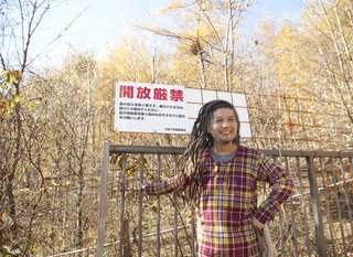 The dreadlocked Ishii Hideaki grins at the gate to the Kobayashi's property.