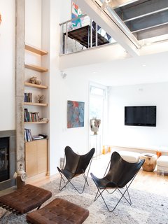 A pair of black leather butterfly chairs face off with Corbusier ottomans in front of the concrete-edged fireplace.
