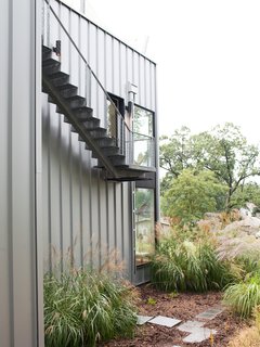 The second Jean Nouvel-inspired staircase lives outside, clinging to the side of the house and leading up to the roof deck, where there's a hot tub shaded by sun sails.