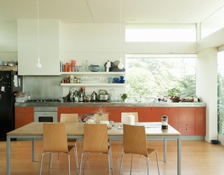 Bach to the Beach - Photo 17 of 30 - The orange-painted MDF cabinets add a pop of color to the sun-washed kitchen.