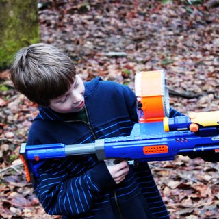 Building the Maxon House: Week 12 - Photo 6 of 11 - Henry takes aim with his Nerf gun while visiting the property. The forested site has provided a perfect backdrop for epic Nerf wars and other makeshift battles. The kids have gotten to know the site and become comfortable in their future backyard during frequent trips over the last couple years.