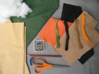 Materials! Here's what you'll need to make it happen:<br><br>1/3 yard green fabric. I used a light cotton twill, but Bonnie used fleece in the book. Anything goes!<br><br>1/4 yard tan fabric<br><br>Orange, black, and tan felt. I bought a square of each, but you don't use much!<br><br>Embroidery floss in green, black, orange, and tan<br><br>Scissors<br><br>Straight pins<br><br>Chalk or white charcoal pencil (optional)<br><br>Sewing machine (optional)