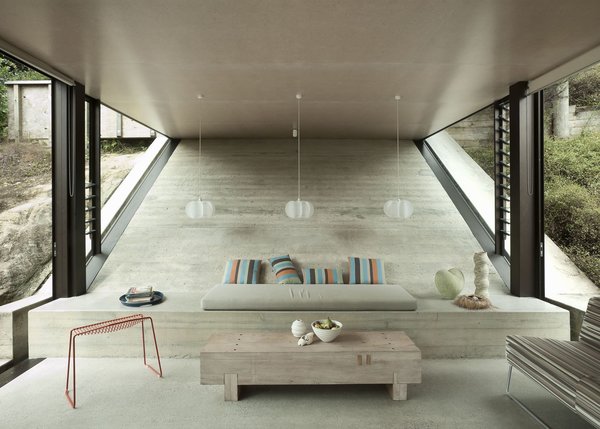 Make Your Parents Happy by Building Them a House - Photo 17 of 25 - The concrete bench in the living area just past the kitchen is built into the sloping wall. The Pedro wire stool is by Craig Bond for Candywhistle.