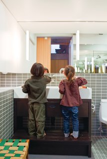 In the bathroom, the twins take advantage of a custom-built Corian sink and wooden base with integrated step when it’s time to wash up.