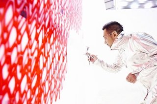 The artist in action with his airbrush gun and silver jumpsuit.