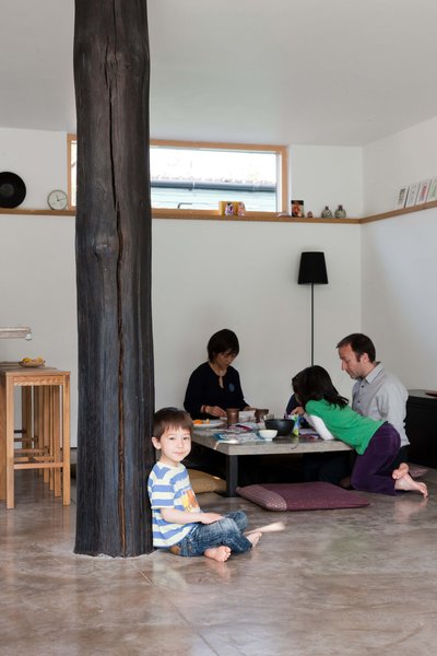 Kaz-ma holds up the charred post while the rest of the family attends to affairs at the sunken table.